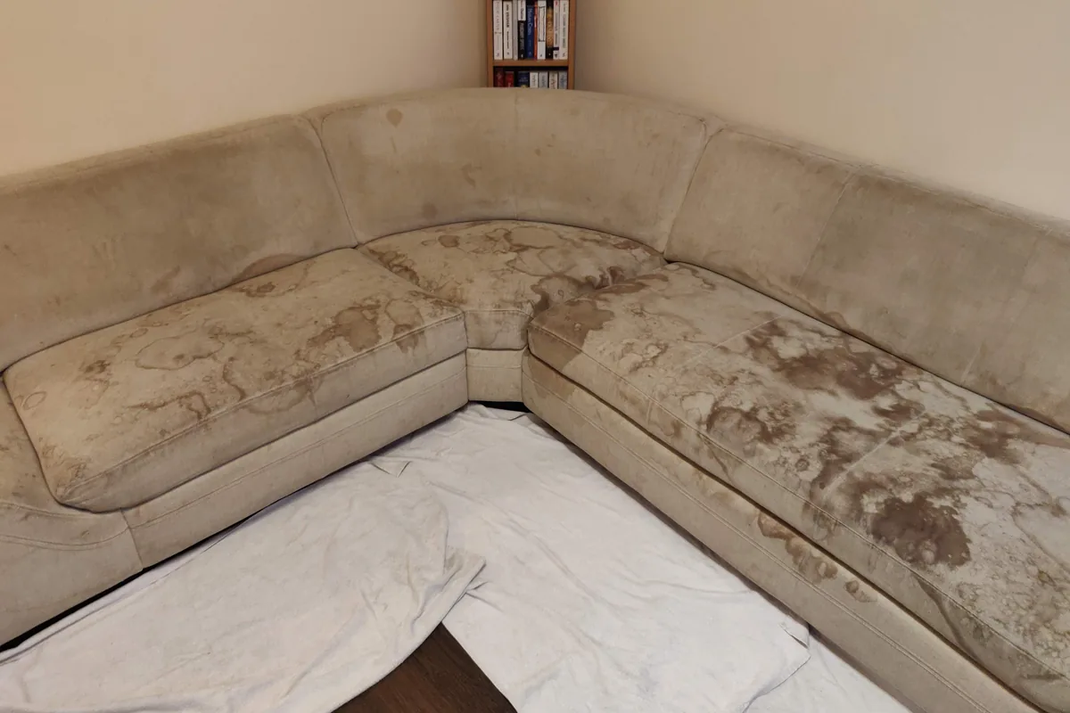 Beige corner lounge, heavy soiling along both seat runs — before cleaning