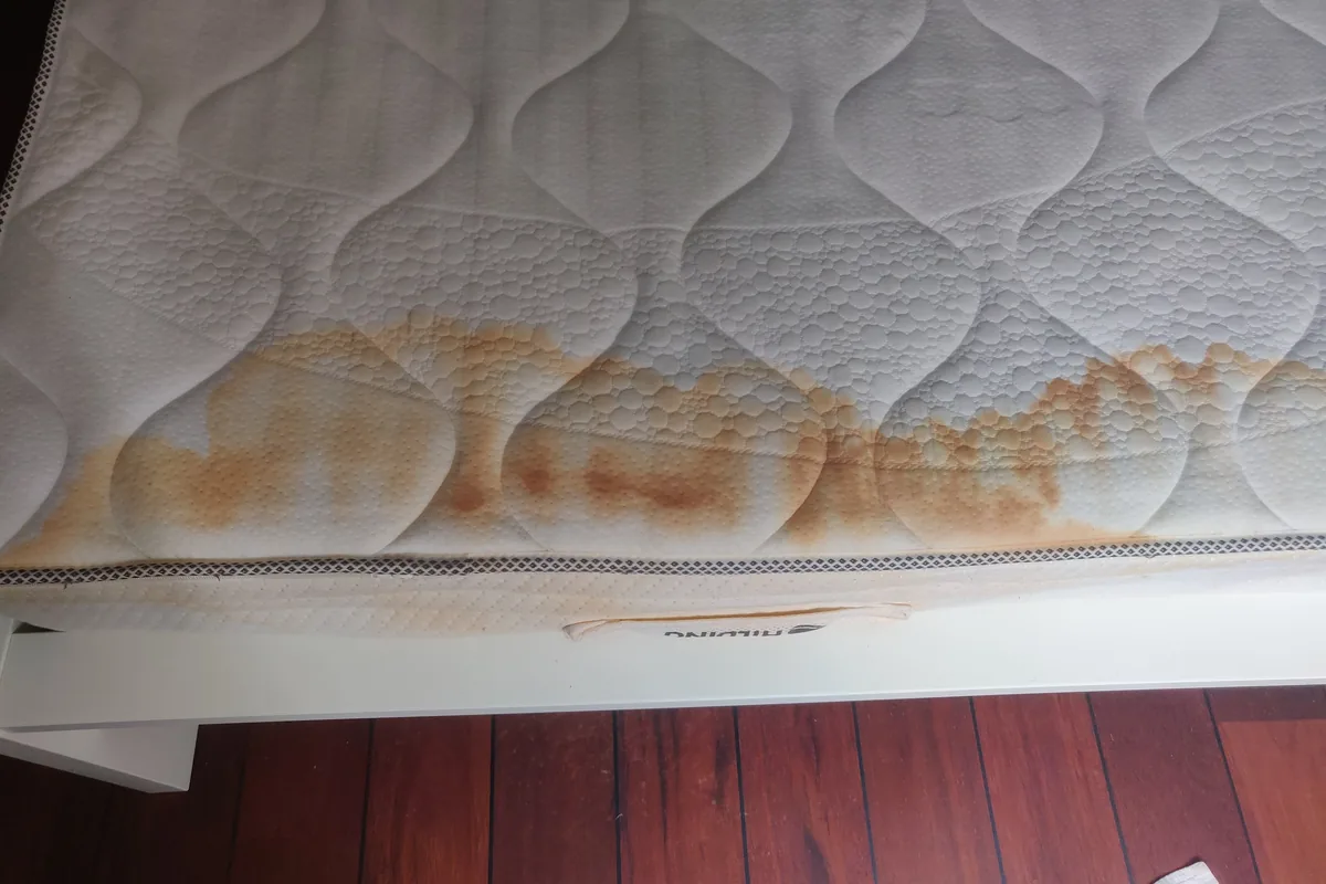 Mattress edge with rust-coloured staining — before cleaning