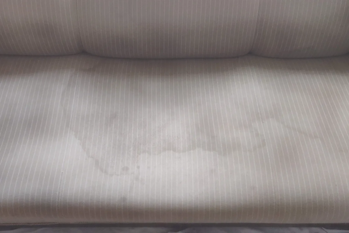 Ribbed white sofa with a stain on the seat — before cleaning