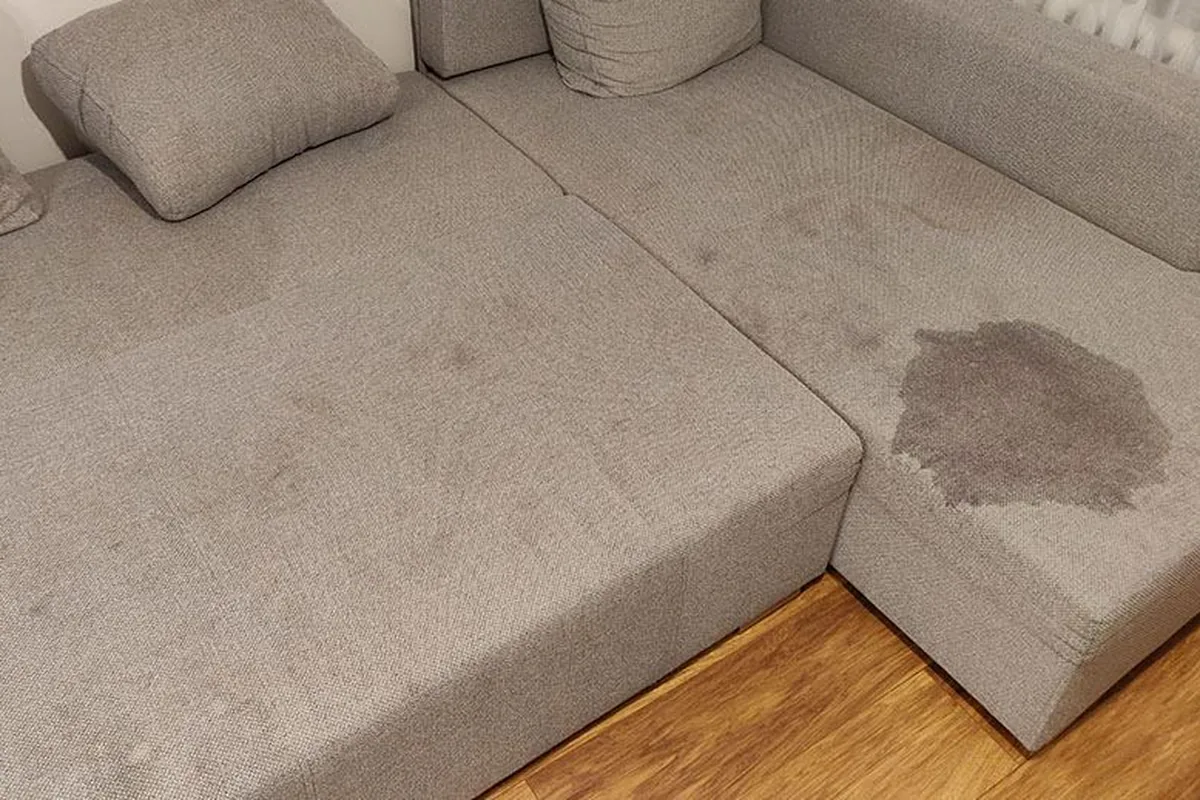 Corner lounge with a dark spill on the seat — before cleaning
